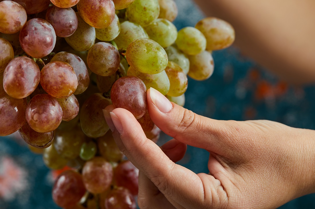 holding-red-grapes-blue-surface.jpg