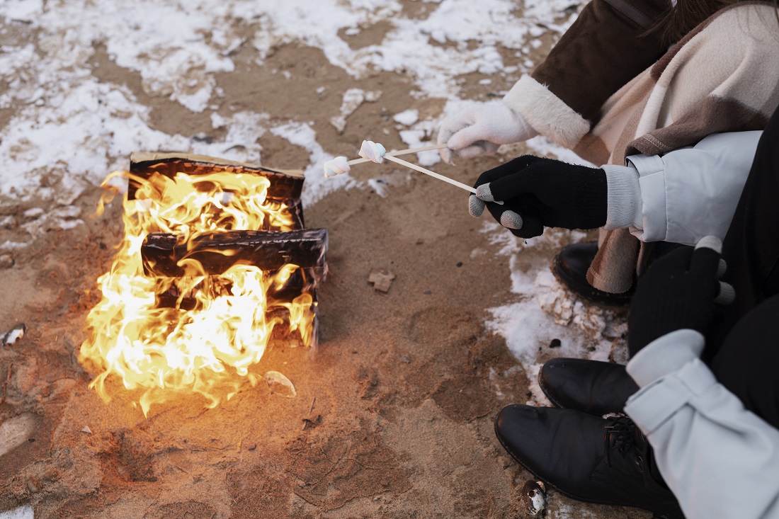 couple-up-roasting-marshmallows-fire-while-winter-road-trip-beach.jpg