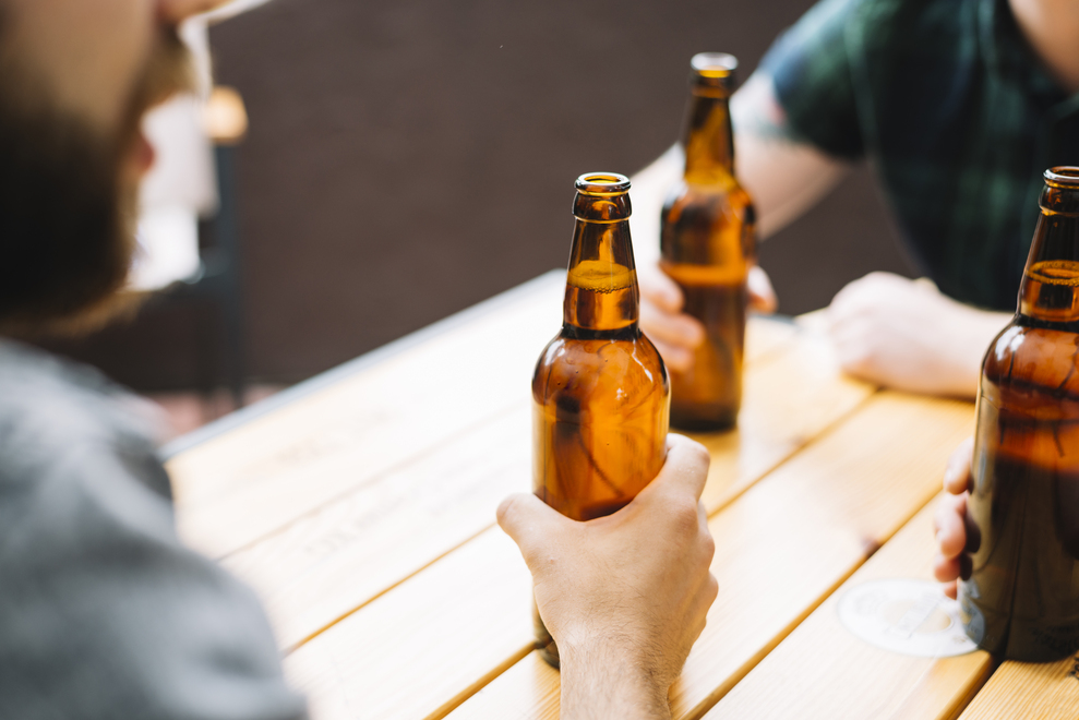 close-up-of-friends-holding-beer-bottles-on-wooden-table (1).jpg