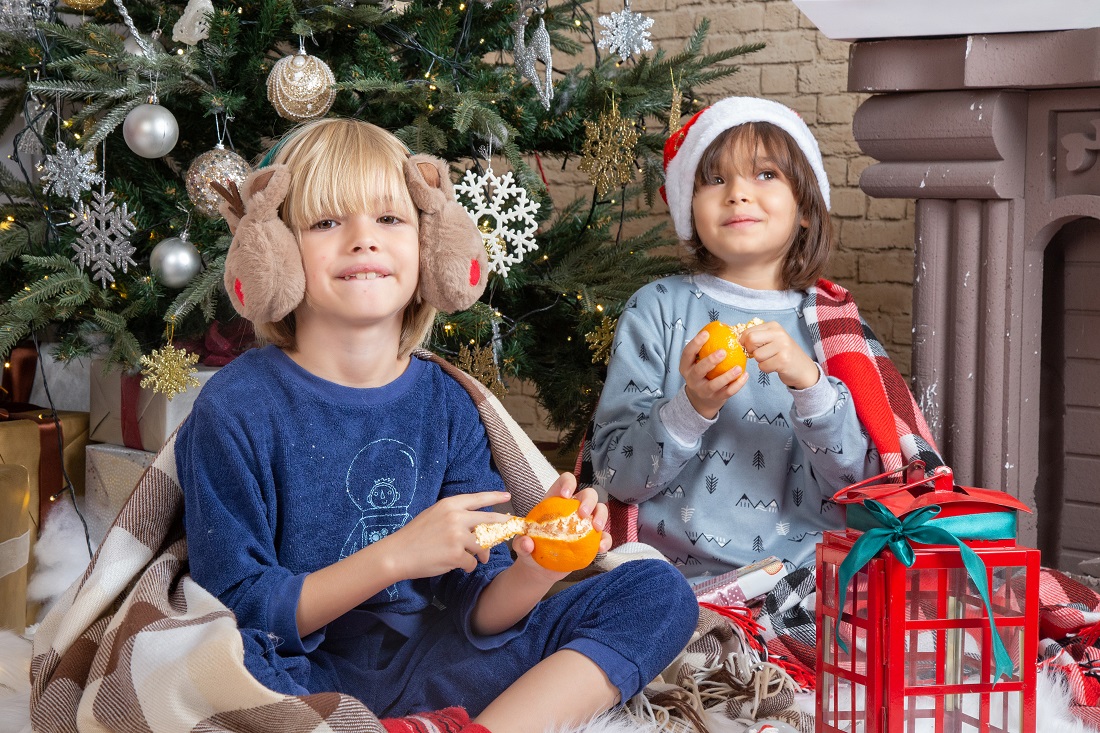 front-view-little-cute-boys-sitting-around-xmas-tree-presents-their-house-eating-tangerine-kid.jpg